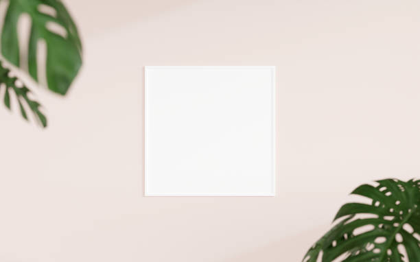istock Clean and minimalist front view square white photo or poster frame mockup hanging on the wall with blurry plant. 3d rendering. 1665923279
