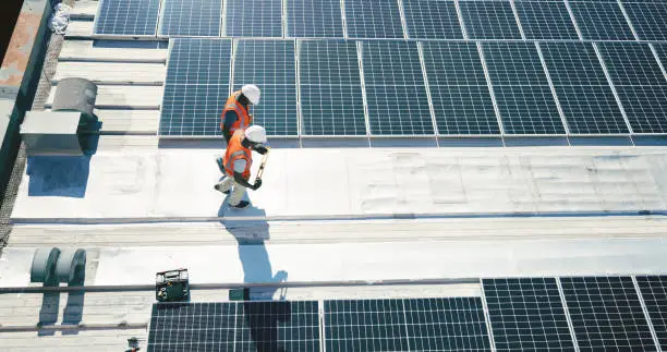 Photo of Clean energy, solar panels and men walking on rooftop for inspection at sustainable business in electricity. Service, sustainability and photovoltaic power on rooftop, engineering team in maintenance