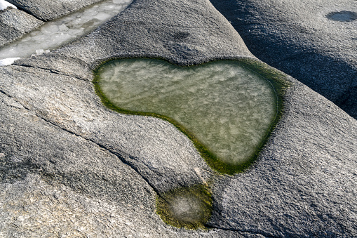 Frozen puddle on large boulder at Utakleiv beach in sunny cold weather, winter, Lofoten, Norway.