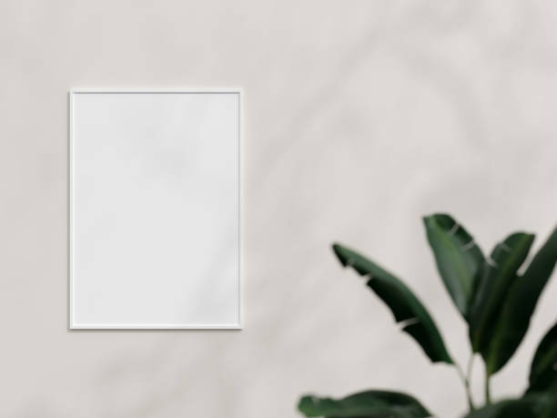 istock Clean and minimalist front view vertical white photo or poster frame mockup hanging on the wall with plant. 3d rendering. 1665944363