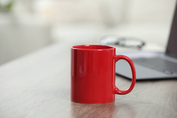 istock Red ceramic mug and laptop on wooden table indoors 1665955168