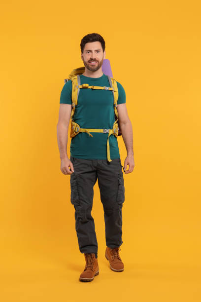 istock Happy man with backpack on orange background. Active tourism 1666011901