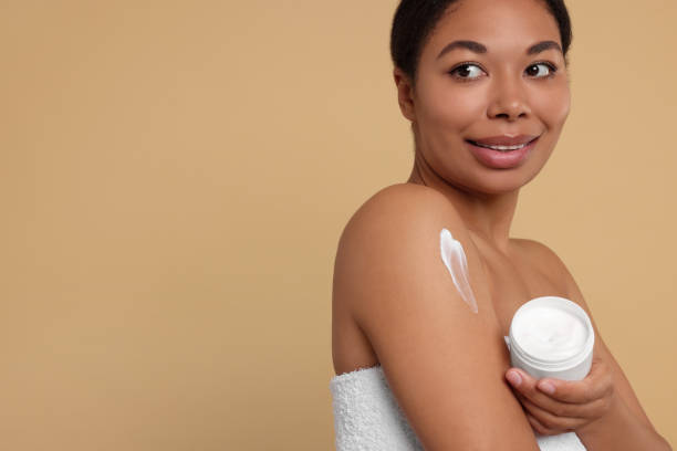 istock Young woman with body cream on beige background. Space for text 1666011925