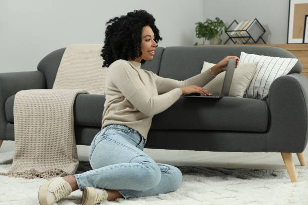 istock Happy young woman using laptop on floor indoors 1666013015