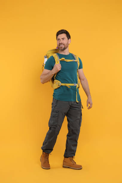 istock Happy man with backpack on orange background. Active tourism 1666014647