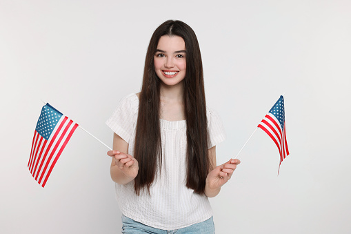 4th of July - Independence Day of USA. Happy girl with American flags on white background