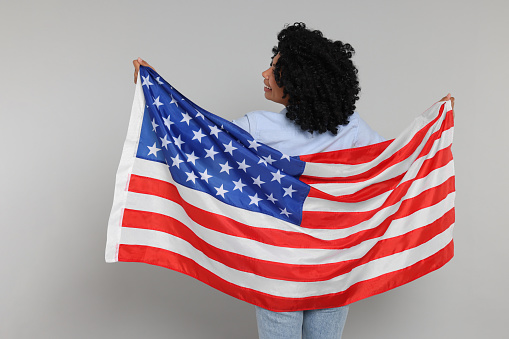 4th of July - Independence Day of USA. Happy woman with American flag on light grey background, back view
