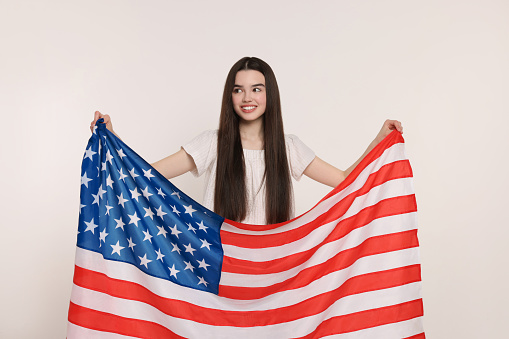 4th of July - Independence Day of USA. Happy girl with American flag on white background
