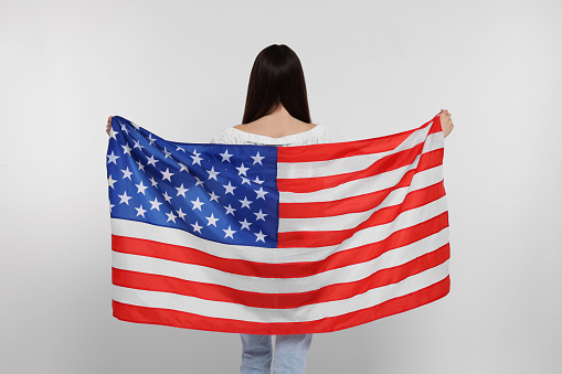 4th of July - Independence Day of USA. Girl with American flag on white background, back view