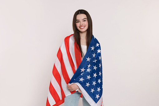 4th of July - Independence Day of USA. Happy girl with American flag on white background