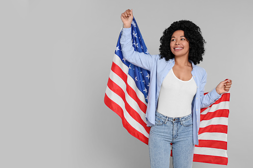 4th of July - Independence Day of USA. Happy woman with American flag on light grey background, space for text