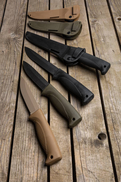 istock Modern hunting knives with rubberized handles and plastic sheaths. Melee weapons for hunting and self-defense. Vintage wooden background. 1666050359