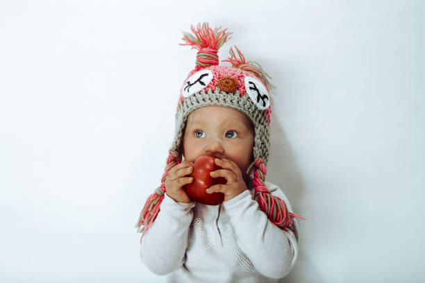 Cute 3 year old girl, making her first chocolate cupcakes at a kitchen table and licking the left over mixture from a wooden spoon