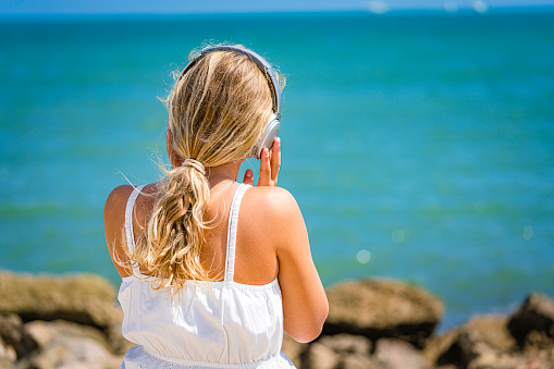 Teen girl listening music by the beach. High resolution 42Mp outdoors digital capture taken with Sony A7rII and Sony FE 90mm f2.8 macro G OSS lens