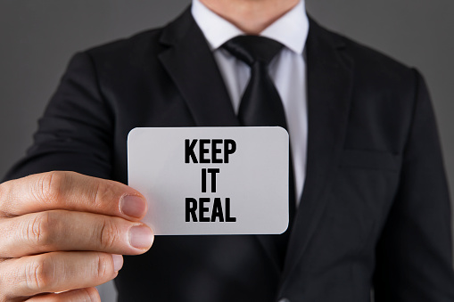 Businessman holding a card with text Keep It Real