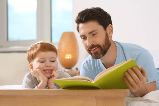 istock Father reading book with his child on bed at home 1666097728