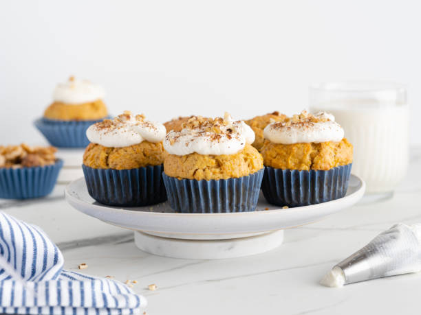 istock Carrot (pumpkin) cupcakes with nuts and cinnamon on white cakestand on white marble table. Seasonal fall dessert. Copy space 1666114393