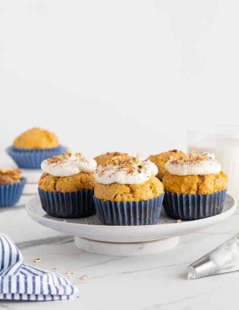 istock Carrot (pumpkin) cupcakes with nuts and cinnamon on white cakestand on white marble table. Seasonal fall dessert. Copy space 1666115436