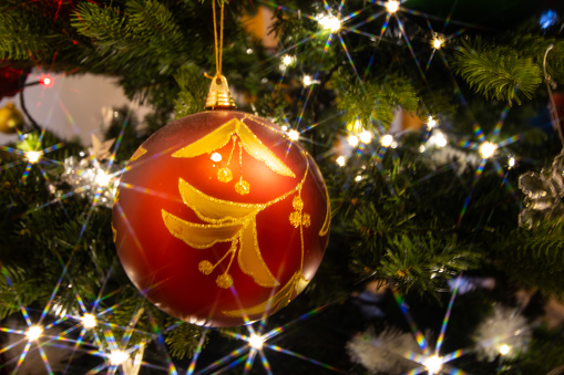 Closeup of a red  and golden Christmas ball hanging in a Christmas tree
