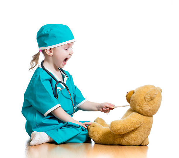 Adorable child dressed as doctor playing with toy over white background