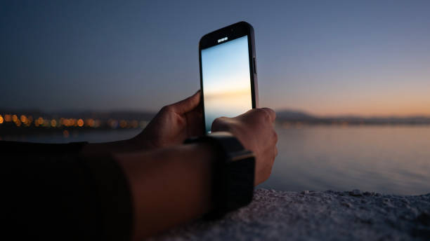 istock Woman's hand taking photos with phone at sunset 1666194657