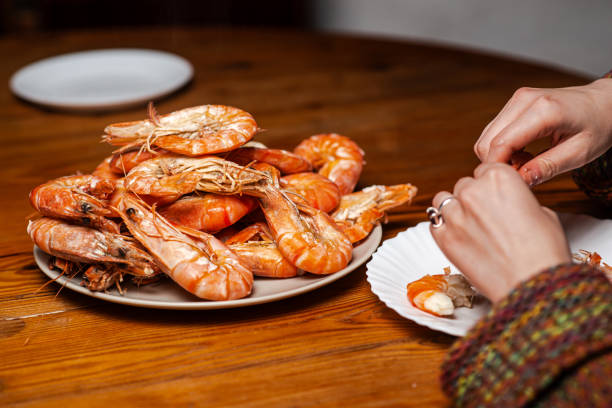 istock Large cooked king prawns on the table. An unrecognizable man is eating shrimp at the table. 1666205515