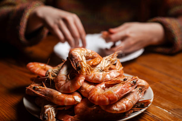 istock Large cooked king prawns on the table. An unrecognizable man is eating shrimp at the table. 1666206623