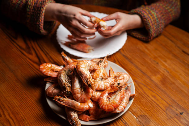 istock Large cooked king prawns on the table. An unrecognizable man is eating shrimp at the table. 1666206634