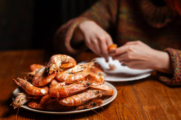 istock Large cooked king prawns on the table. An unrecognizable man is eating shrimp at the table. 1666206636