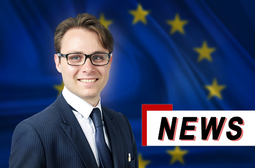 News anchor, tells the latest news, smiling, against the background of the flag of European union. Media and propaganda.