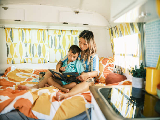 istock Asian mother and son reading book inside camping trailer 1666225937