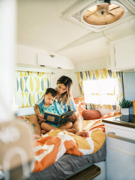 istock Asian mother and son reading book inside camping trailer 1666225943