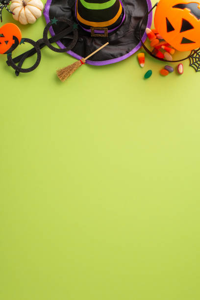 istock Enthralling kids' Halloween night celebration idea. Overhead vertical shot of sweets, witch hat and Halloween-themed embellishments on an isolated green setting, allowing space for adverts or text 1666280442