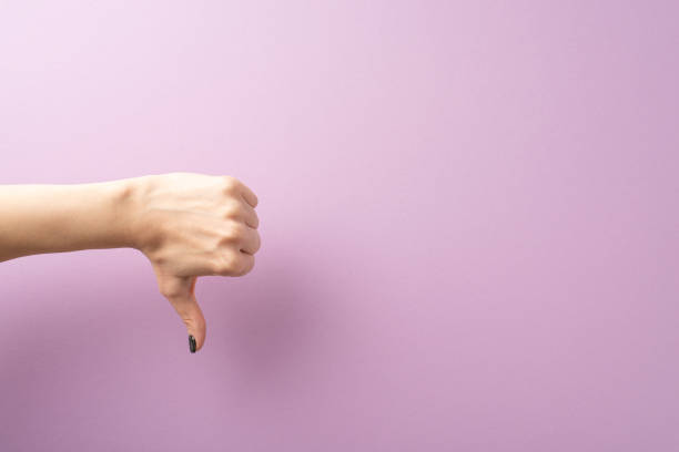 istock Viewed from first person, a young woman's hand showcases a thumbs-down gesture on a lilac expanse. Space provided for text or adverts, aligning with the expressive gestures concept 1666280444
