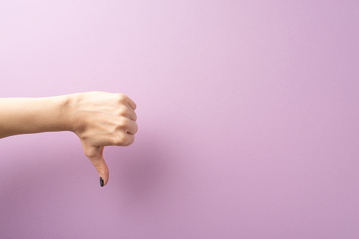 Viewed from first person, a young woman's hand showcases a thumbs-down gesture on a lilac expanse. Space provided for text or adverts, aligning with the expressive gestures concept