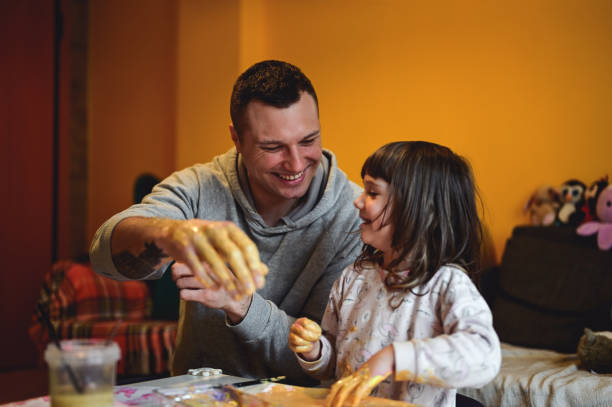 istock father with daughter laughing while painting. 1666290712