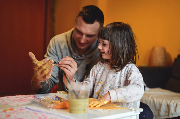 istock father learning to his daughter how to paint with fingers. 1666291354