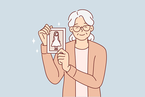 Elderly woman shows photo of little girl and smiles, nostalgic and remembering past. Grandmother demonstrates photography of granddaughter and wishes to become young, experiencing nostalgic feelings