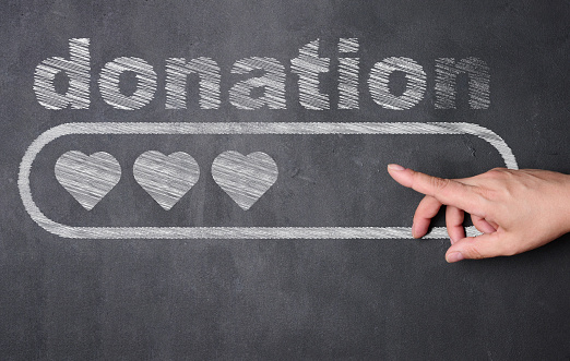 A hand pointing at a blackboard with the word donat written on it, below the word is a rectangular block with three hearts inside