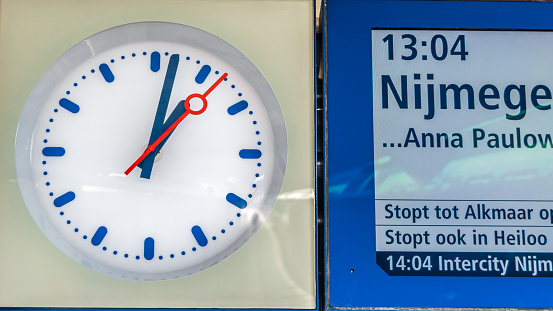 Den Helder, The Netherlands - August 25, 2013: Clock and sign announcing the departure of a train on a platform at the train station in Den Helder, North Holland province, the Netherlands