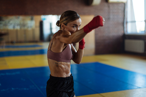 With intense focus, a young woman is engaged in boxing training