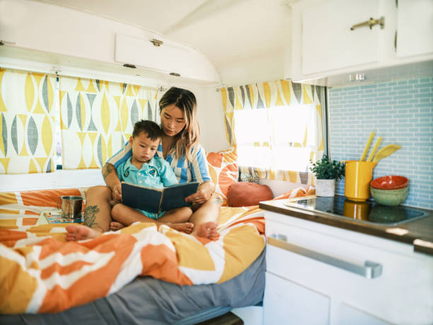 istock Asian mother and son reading book inside camping trailer 1666399465