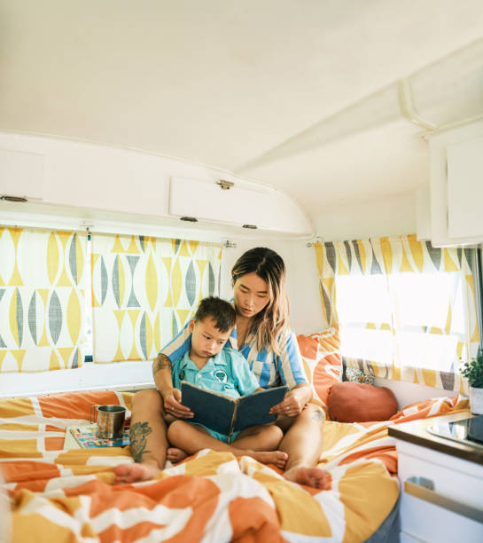 istock Asian mother and son reading book inside camping trailer 1666399486