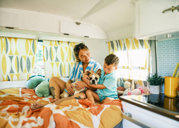 istock Asian mother, son and small dog playing on bed inside camping trailer 1666400588