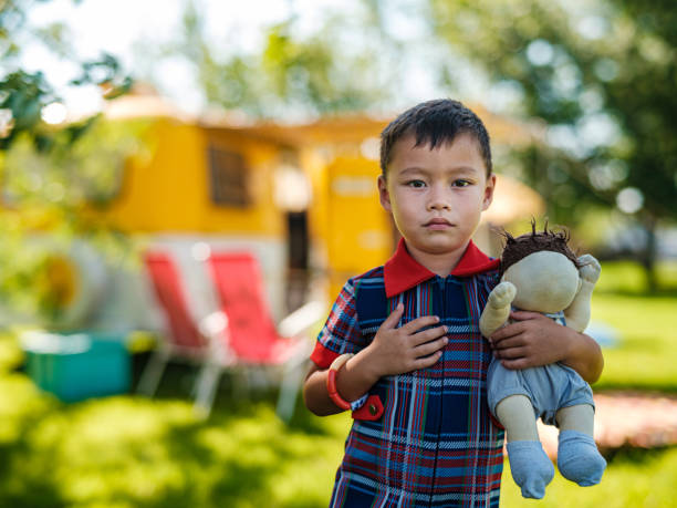 Mixed race boy enjoying camping in summer. He is dressed in retro casual clothing. Exterior of camping site in summer time.