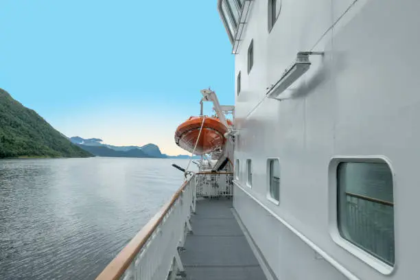 early morning view over the ship bow with blue sky to the fjord with rising sun in Norway