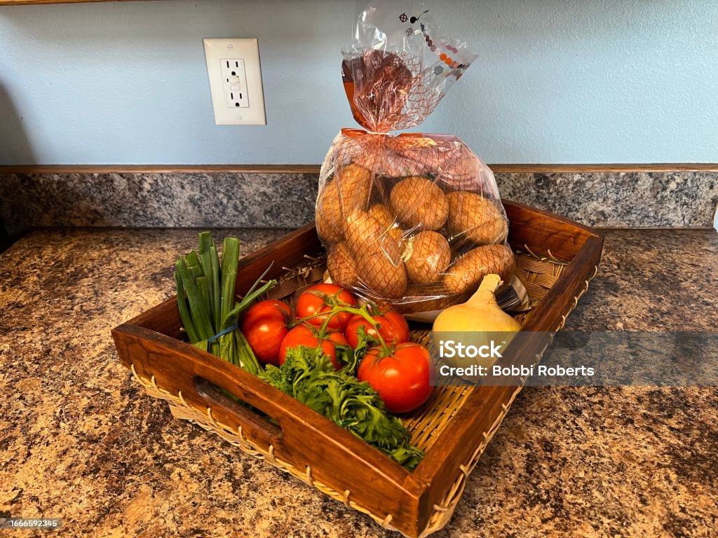 Vegetable Basket Potatoes, tomatoes, onion, green onions, and herbs in a basket. Basket Stock Photo