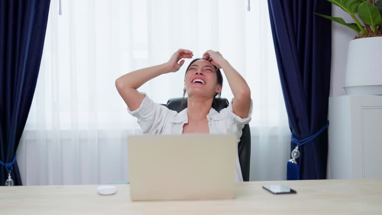 Happy euphoric young asian woman celebrating winning or getting ecommerce shopping offer on computer laptop. Excited happy girl winner looking at notebook celebrating success