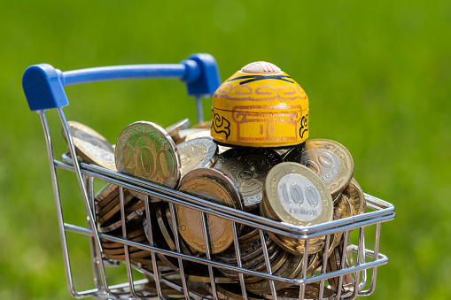 Miniature yurt (traditional nomad house) and 100 and 200 Kazakh tenge coins in a miniature shopping cart from a supermarket