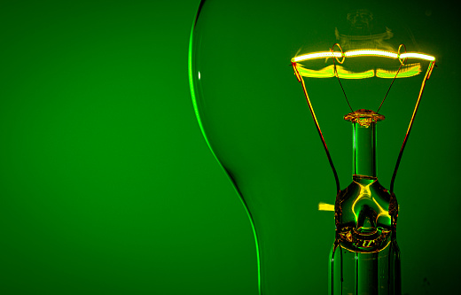 Close up glowing light bulb green background